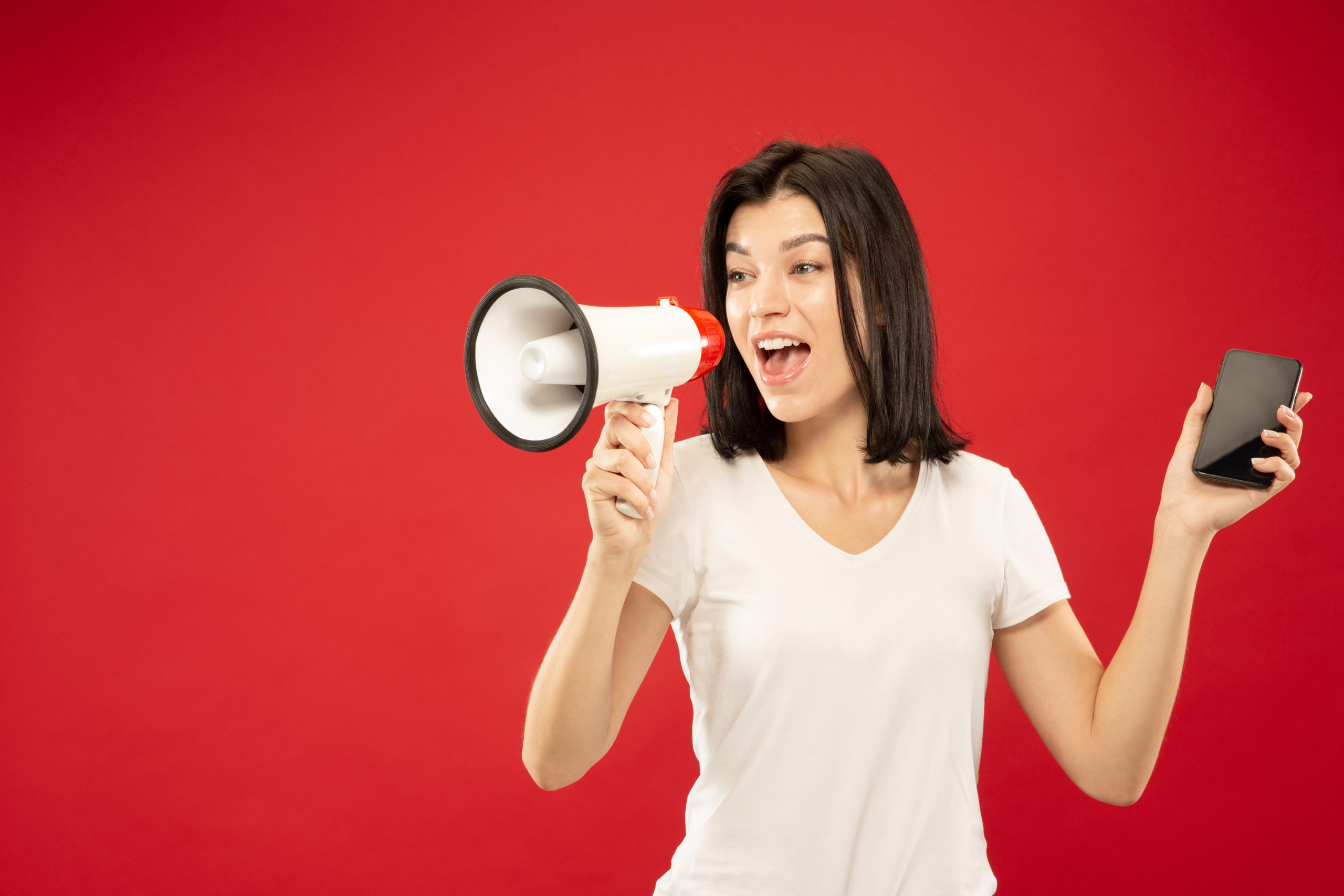 Caucasian young woman’s half-length portrait on red background